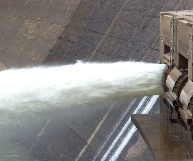 Wasserkraftwerk mit austretendem Wasser, das eine große Wolke bildet, und einer stromerzeugenden Maschine auf der rechten Seite.