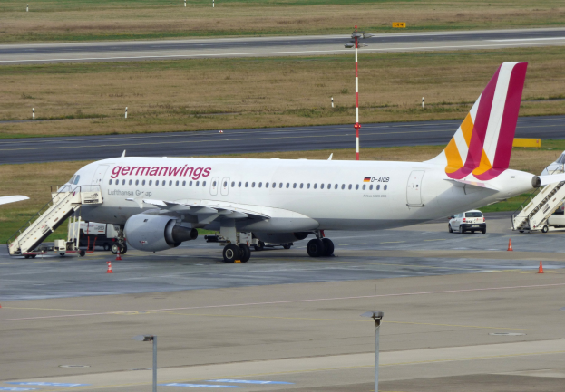 Germanwings Airbus A320-200 auf dem Frankfurter Flughafen geparkt mit Bodenfahrzeugen, Verkehrskegeln, Pfählen und Gras im Hintergrund.
