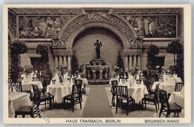 Schwarz-weißes Foto eines alten Berliner Restaurant-Interieurs mit Tischen, die mit Vasen gedeckt sind, einer Statue im Hintergrund, skulptierten Wänden und Text unten.