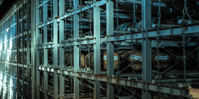 Ein großes Lager mit zahlreichen Fässern, die ordentlich in einem Gestellsystem gestapelt und miteinander verbunden sind.