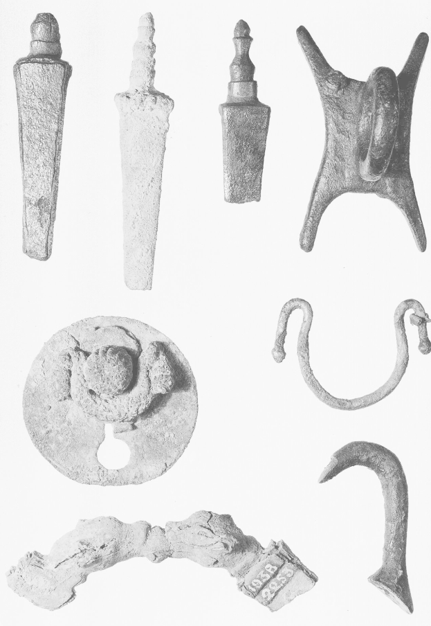 Schwarzes und weißes Bild von neolithischen Artefakten, einschließlich Metallobjekten, auf einer weißen Oberfläche angezeigt.