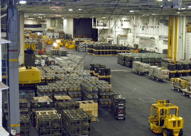 Ein großes Lager voller Numerous Trucks, Container, Menschen, Lichter, Stangen und andere Gegenstände mit einem sichtbaren Rad.