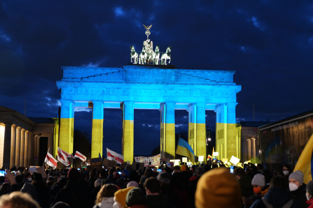 Menge mit Fahnen und Plakaten vor dem Brandenburger Tor, mit einer Fahne auf der rechten Seite.