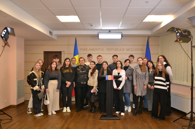 Gruppe von Menschen vor einem Rednerpult mit Mikrofon auf dem Moldova-Jugendkongress 2018, umgeben von Fahnen, einer Wand mit Text, einer Tür, Deckenleuchten und Scheinwerfern.