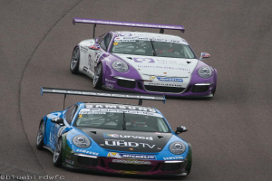 Zwei Autos auf einer Straße außerhalb einer Stadt mit Text in der linken unteren Ecke.