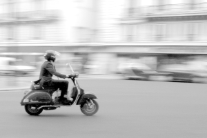 Eine Person, die einen Roller auf einer Straße fährt.