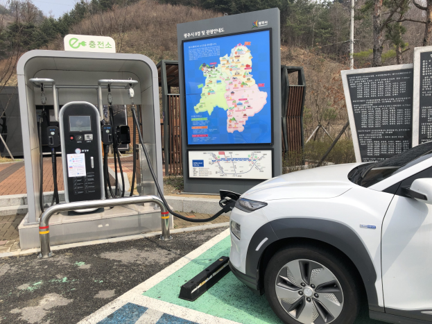 Elektroauto-Laden an einer Station in Seoul, Südkorea, umgeben von Bäumen mit dem Himmel im Hintergrund.