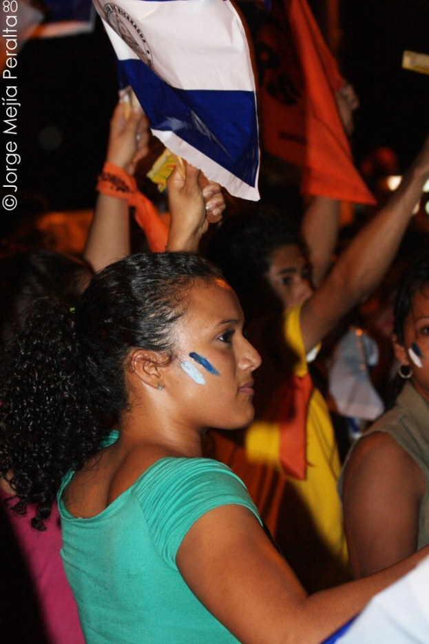 Frauen in grünen T-Shirts mit weißem Stoff während einer Demonstration, mit mehreren anderen Mädchen im Hintergrund.