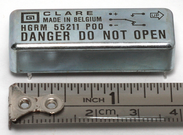 Metallbox mit der Aufschrift "Danger Do Not Open" neben einer Messlatte auf einer weißen Oberfläche