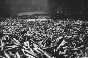 Ein Schwarz-Weiß-Foto eines großen Haufens von Kugeln im Vordergrund, mit einer Hütte und Bäumen im Hintergrund und dem Text "Weltkrieg" unten.