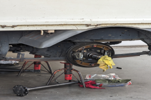 Ein Lastwagen in einer Garage geparkt mit einem gelben Tuch bedeckt, umgeben von verstreuten Werkzeugen und Gegenständen auf dem Boden.