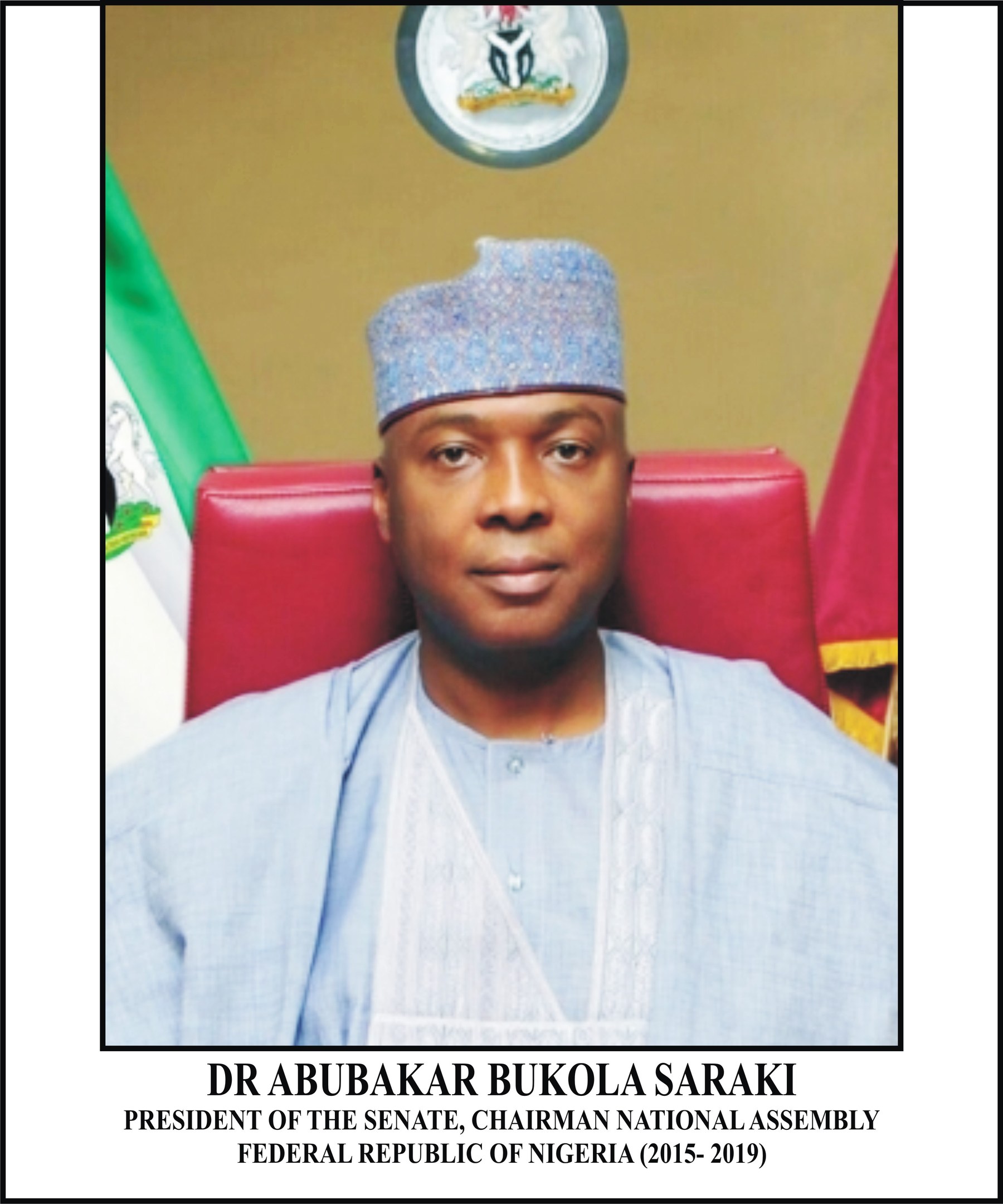 Dr. Abubakar Bukola Saraki, Präsident des Senats, sitzt in einem blauen Gewand und Hut, mit zwei Flaggen und einem Logo an der Wand hinter ihm und einem Rahmen mit Namen unten.