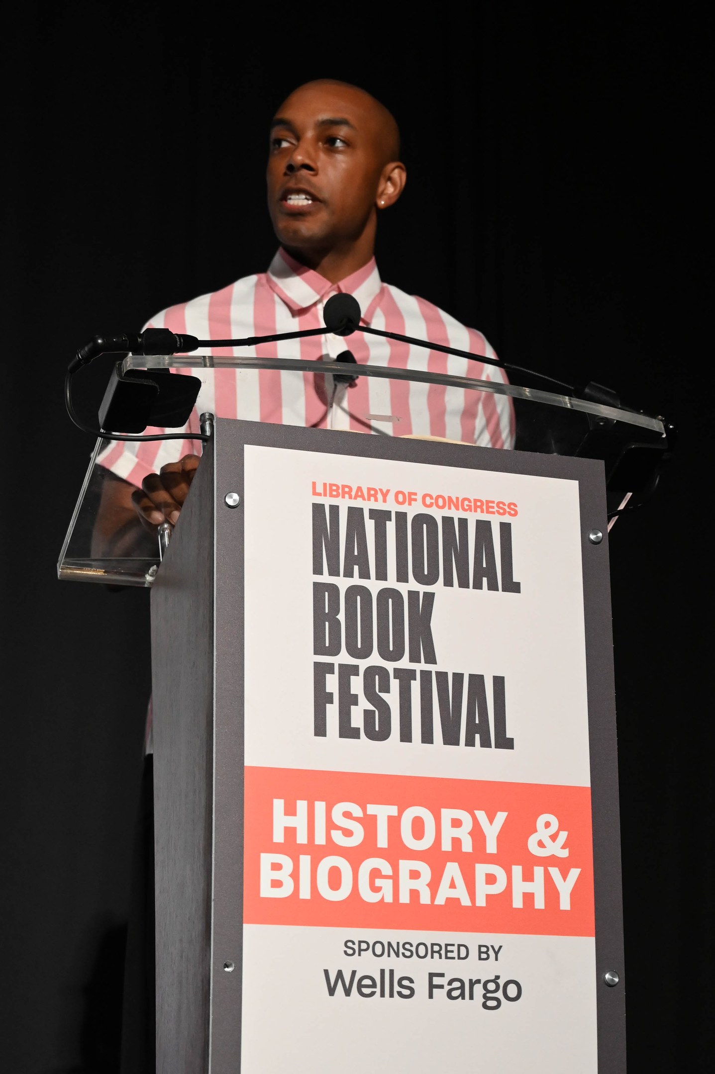 Ein Mann steht an einem Rednerpult mit einem Mikrofon und spricht auf einer Abendveranstaltung mit dem Titel "National Book Festival History & Biography".