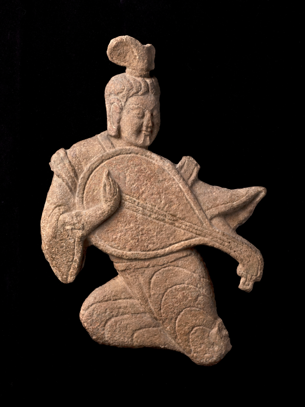 Eine steinerne Skulptur eines Mannes in einem langen Gewand, der ein Musikinstrument spielt und einen friedlichen Ausdruck sowie geschlossene Augen hat, vor einem schwarzen Hintergrund.