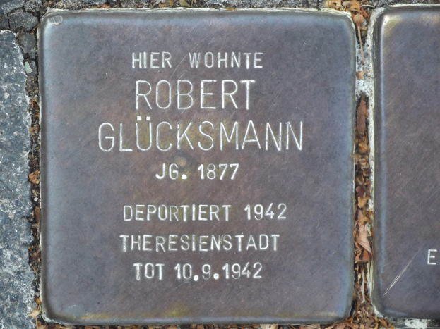 Steintafel auf dem Boden vor einem Gebäude mit der Inschrift "Robert Glücksmann".