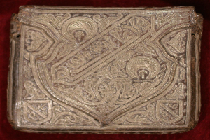 Altes Buch mit goldener Hülle, das auf einem roten Samtgrund mit kunstvollen Verzierungen prunkt.