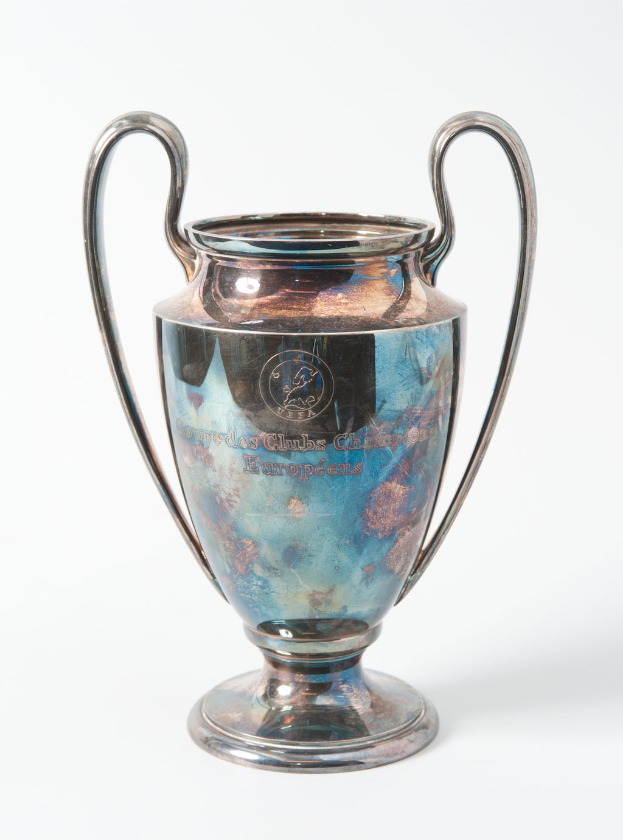 Ein UEFA-Champions-League-Pokal aus Silber und Blau mit zwei Griffen, darauf eingraviert mit seinem Namen, vor einem weißen Hintergrund dargestellt.