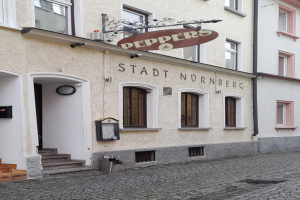 Gebäude mit der Aufschrift "Stadt Nurnberg" mit Treppe zu einer Tür und Fenstern, mit einem Müllcontainer im Vordergrund.