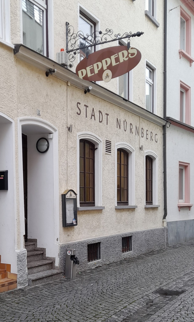 Gebäude mit der Aufschrift "Stadt Nurnberg" mit Treppe zu einer Tür und Fenstern, mit einem Müllcontainer im Vordergrund.