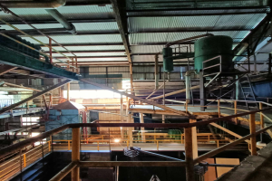 Ein großes industrielles Fabrik-Innenraum-Foto, das verschiedene Maschinen, Geländer, Treppen, Pfosten und Geräte zeigt, was auf eine Pyrolyse-Anlage für Altreifen hindeutet.