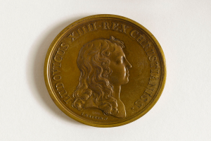 Eine Goldmedaille mit dem Bild einer Frau und der Inschrift "Medaille" auf einem weißen Hintergrund.