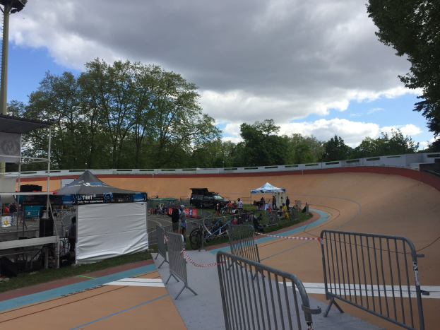 Gruppe von Radfahrern, die BMX-Räder auf einer Schmutzspur bei den UCI BMX-Weltmeisterschaften 2018 fahren, mit Zuschauern, Zelten und Fahrzeugen im Hintergrund.