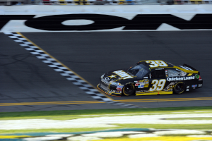 Ein Rennwagen auf einer Straße mit Gras am Boden, mit Text auf dem Auto.
